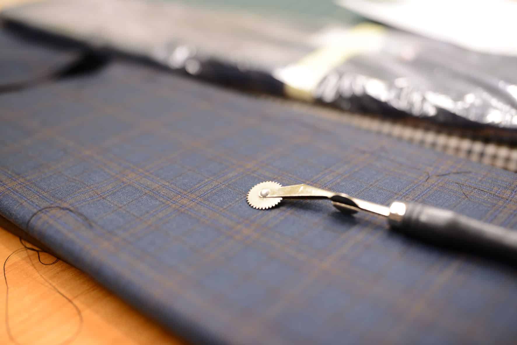 nożyk do cięcia nici na kawałku materiału w drobną kratkę
